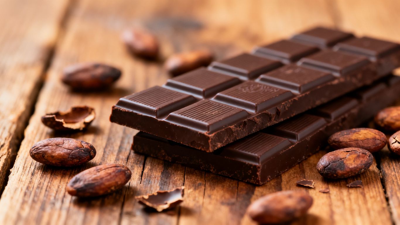 Artisanal chocolate bars and cacao beans on wood.